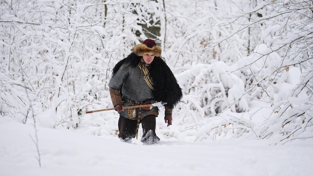 Homem viking indo na floresta de inverno. ele se vestiu com roupas medievais.