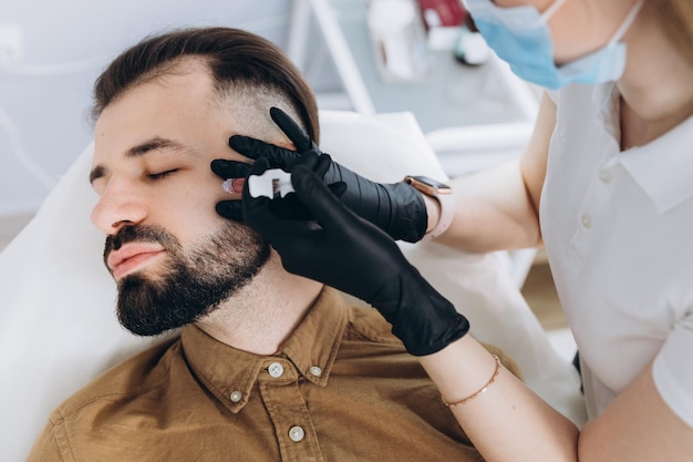 homem visitando clínica estética obtendo preenchimento de lábios closeup Homem atraente tendo injeção de beleza