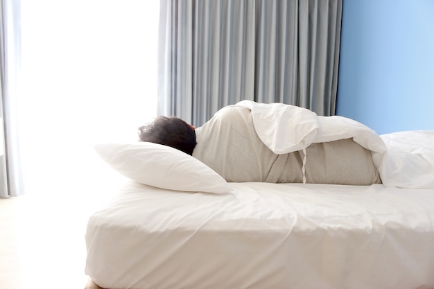 Homem volta a dormir na cama no quarto do hotel