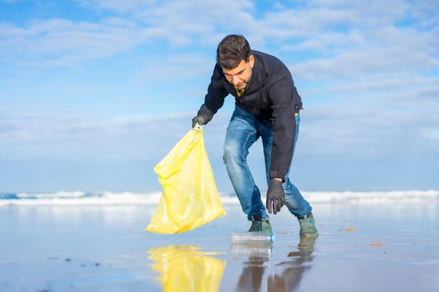 Homem voluntário coletando lixo ou plástico na praia Conceito de ecologia oceanos limpos