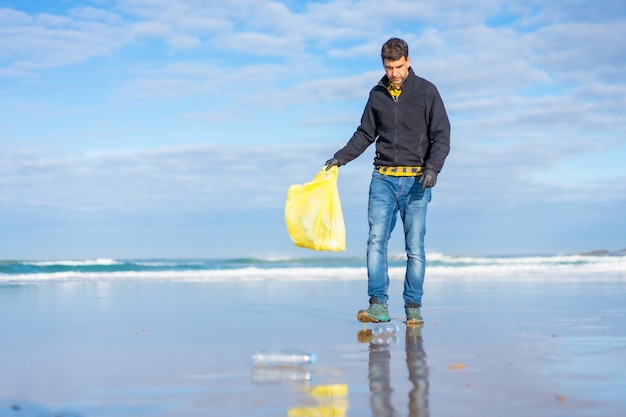 Homem voluntário coletando lixo ou plástico no conceito de ecologia de praia