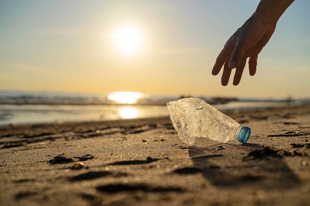 Homem voluntário e garrafa de plástico limpam o dia coletando resíduos na praia do mar