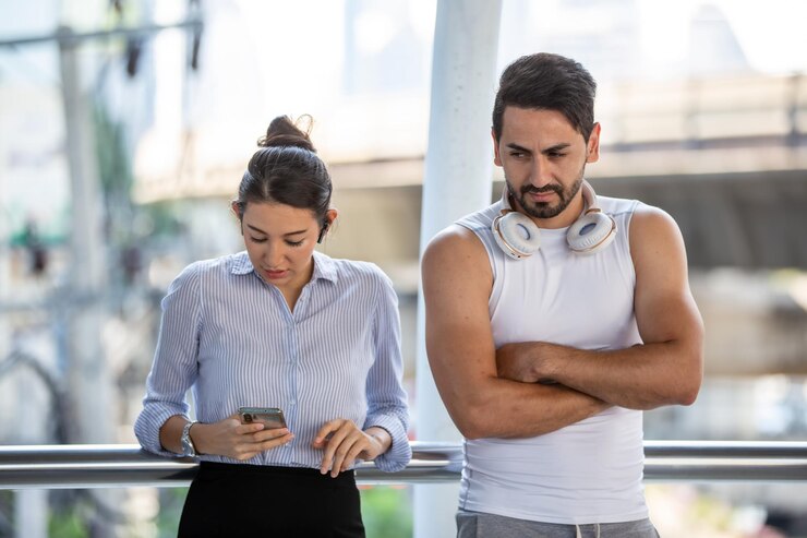Foto homem zangado olhando para a mulher usando o telefone enquanto estava de pé junto ao corrimão