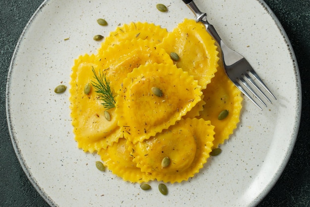 Foto homemade pumpkin ravioli mit butter auf einem dunklen beton-hintergrund