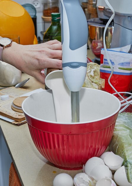 Homemaker batendo pancake batter na cozinha com blender e tigela