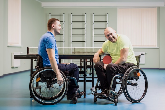 Homens adultos com deficiência rindo depois de jogar tênis de mesa