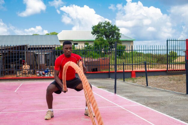 Homens africanos com cordas de batalha exercitam-se no ginásio de fitness