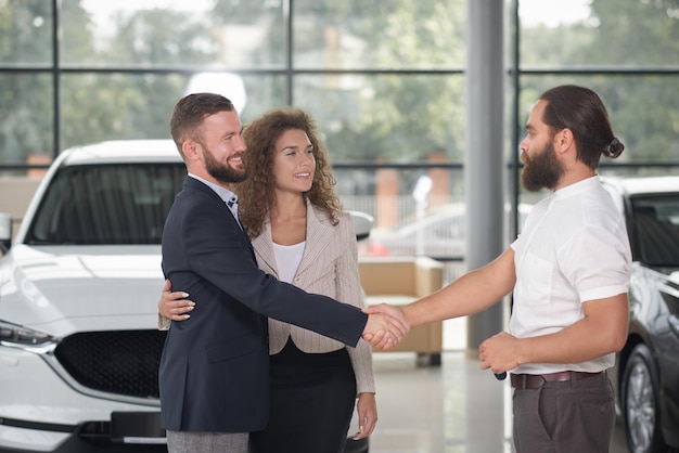 Homens apertando as mãos casal comprando automóvel