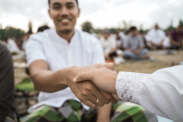 Homens asiáticos apertam as mãos após a oração do eid