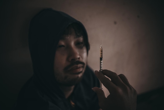 Homens asiáticos são viciados em drogas para injetar heroína em suas próprias veias Droga Flakka ou droga zumbi é uma ameaça à vida perigosaTailândia não ao conceito de drogasAs drogas do bandido na desolação