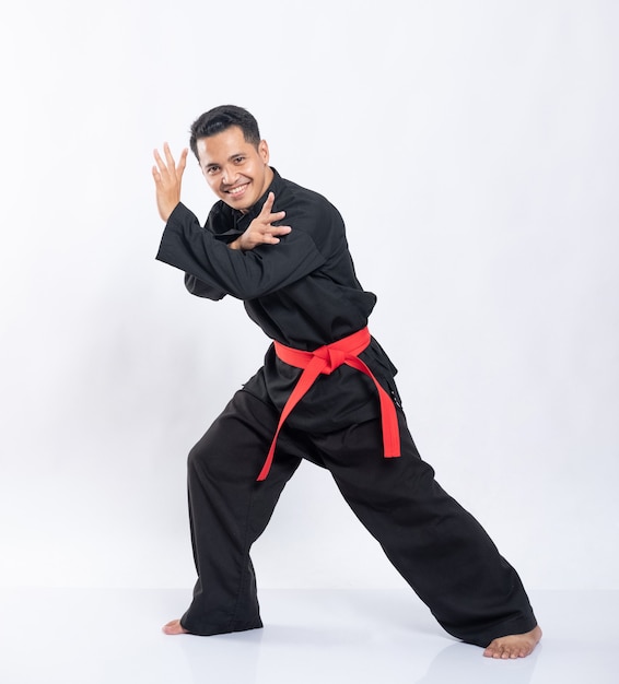 Homens asiáticos usando uniformes de silat pencak com cintos vermelhos fazem movimentos de esquiva