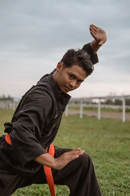 Homens asiáticos vestindo uniformes de silat pencak com movimentos pasang na natureza