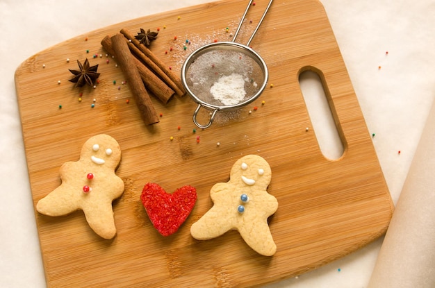 Homens assados e biscoitos de coração vermelho em uma placa de madeira para assar O conceito de amor