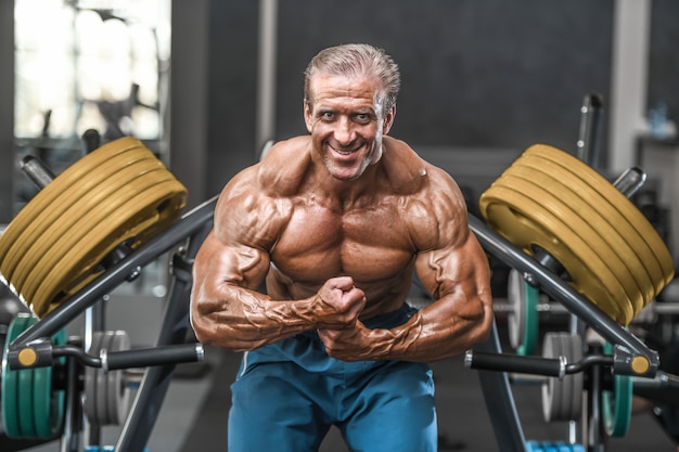 Homens atléticos brutal envelhecidos fisiculturista forte bombeando músculos com halteres