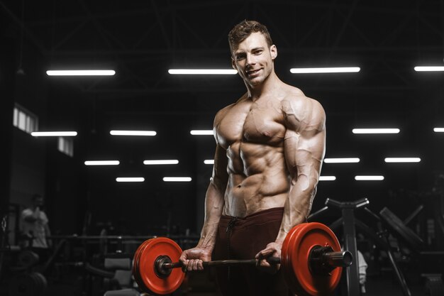 Homens atléticos fortes bonitos, bombeando os músculos treino barra conceito de musculação