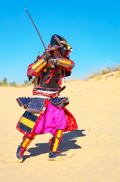 Homens com armadura de samurai e espada correndo na areia