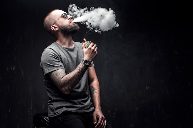 Foto homens com barba em óculos de sol vaping.