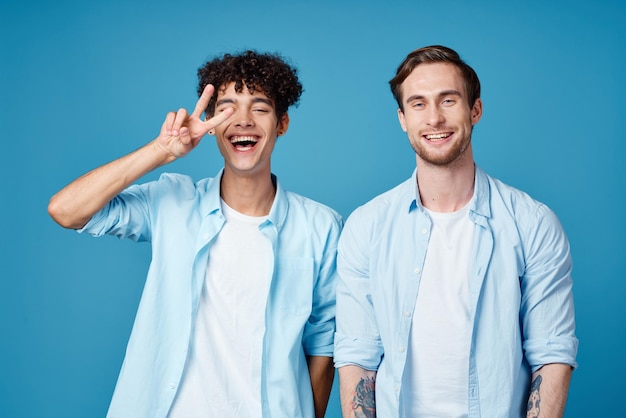 Homens com camisetas idênticas e camisetas brancas em um fundo azul conversando com amigos, visualização recortada