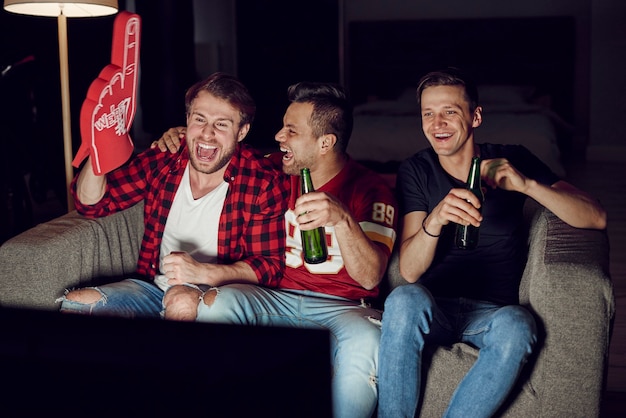 Homens com mão de espuma e cerveja em festa de futebol