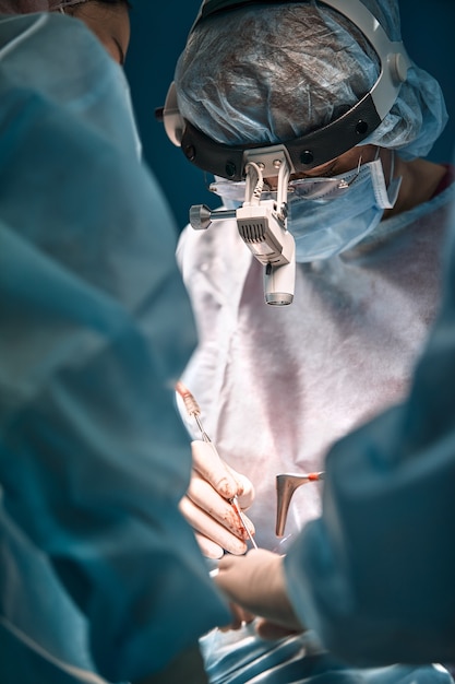 Foto homens da rinoplastia, as mãos enluvadas do cirurgião seguram os instrumentos durante a cirurgia de nariz. médico com luvas segura um instrumento médico durante a rinoplastia.