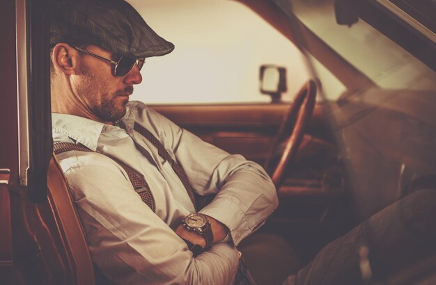 Homens de aparência retrô sentados dentro de carros clássicos