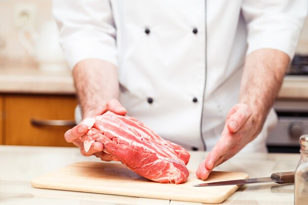 Homens de cozinheiro profissional mostram um pedaço de carne