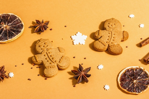 Foto homens de gengibre de natal com especiarias perfumadas. decoração festiva tradicional de ano novo. luz dura na moda, sombra escura, fundo bege, configuração plana, close-up