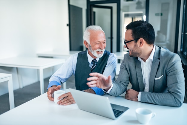 Foto homens de negócio sênior e júniors de sorriso no trabalho.