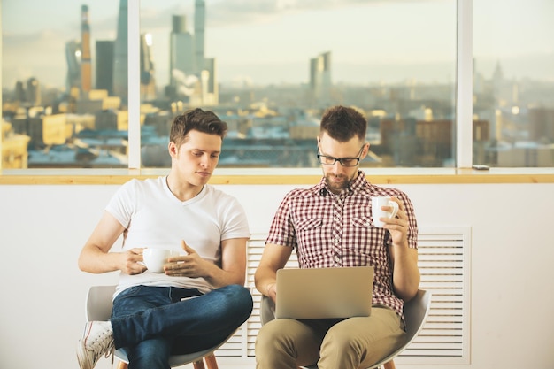 Homens de negócios bonitos usando laptop juntos