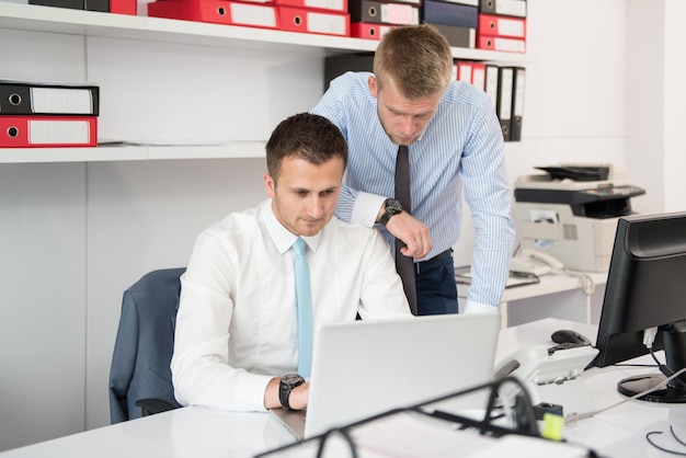 Homens de negócios jovens felizes trabalham no escritório moderno no computador