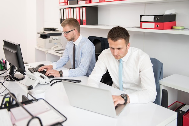 Homens de negócios jovens felizes trabalham no escritório moderno no computador