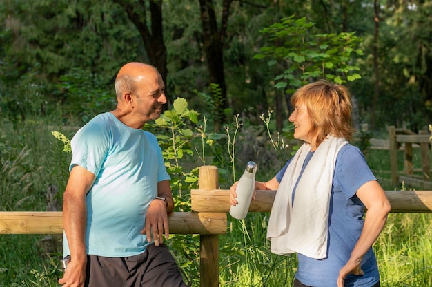 Foto homens e mulheres idosos olhando um para o outro conversando e sorrindo depois de trabalhar em um ambiente natural