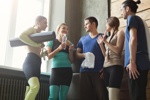 Homens e mulheres jovens em roupas esportivas, conversando antes do treinamento físico. Grupo de jovens amigos desportivos no clube desportivo, pov. Conceito de estilo de vida ativo e saudável