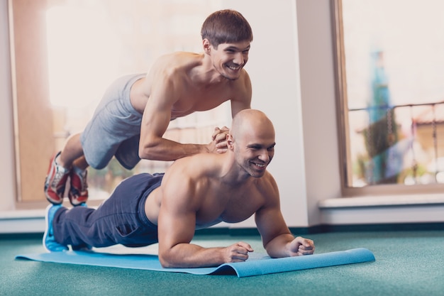 Homens felizes realizam exercícios físicos difíceis.