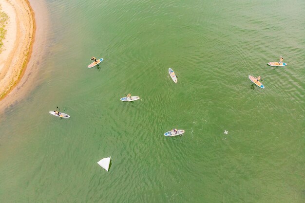 Homens fortes flutuando em pranchas de SUP em uma bela baía em um dia ensolarado Vista aérea dos homens atravessa a baía usando o paddleboard Competições de esportes aquáticos