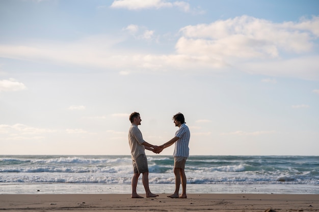 Foto homens gays de tiro completo de mãos dadas na praia