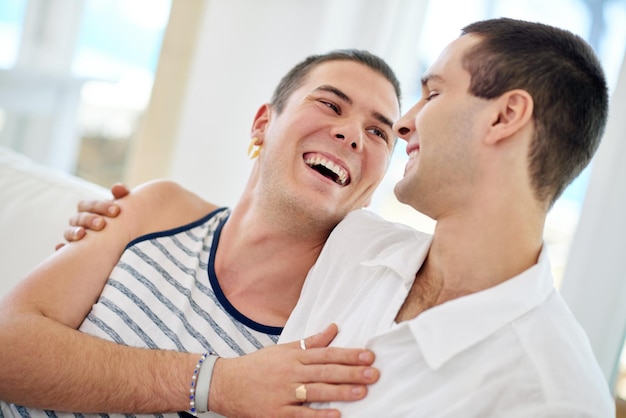 Foto homens gays e casais felizes relaxam com conexão de ligação ou orgulho queer para o amor ou conforto homossexual homens abraçam e riem piada no apartamento para relacionamento casamento ou descanso