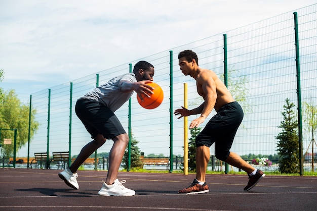 Homens jogando basquete urbano, ângulo baixo