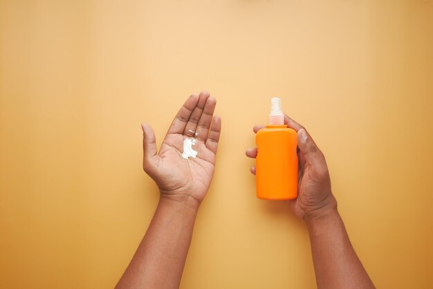 homens jovens usando creme protetor solar em fundo de cor laranja