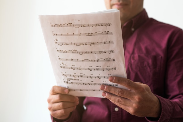 Homens lendo partituras em casa, foquem na partitura e nas suas mãos. branco