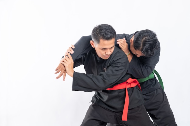 Foto homens lutadores em uniformes pretos de silat pencak lutam segurando e travando as mãos do oponente