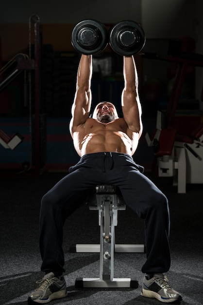 Foto homens maduros fazendo exercícios de supino inclinado com halteres na academia