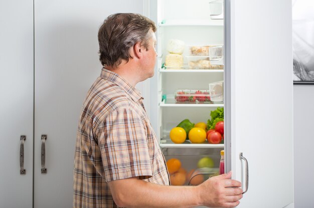 Homens maduros na geladeira com comida