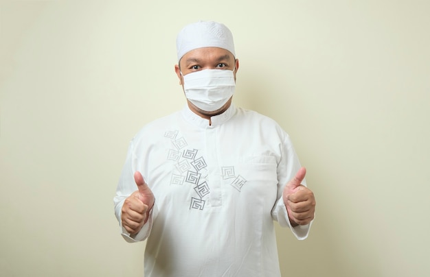 homens muçulmanos asiáticos gordos usando máscaras com gestos confiantes de polegar para cima e apontando para as máscaras