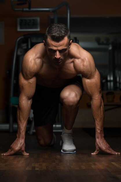 Homens musculosos fortes ajoelhados no chão quase como a posição inicial do velocista