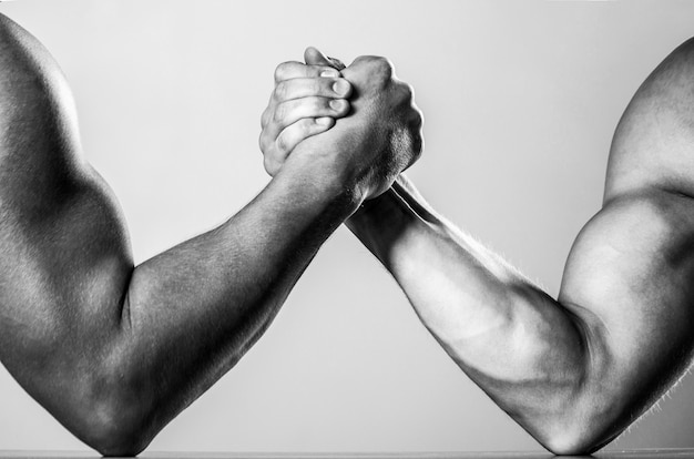 Foto homens musculosos medindo forças, braços. luta livre, compita. mãos ou braços de homem. mão musculosa. wrestling de braço de dois homens. rivalidade, close up da queda de braço masculina. preto e branco.