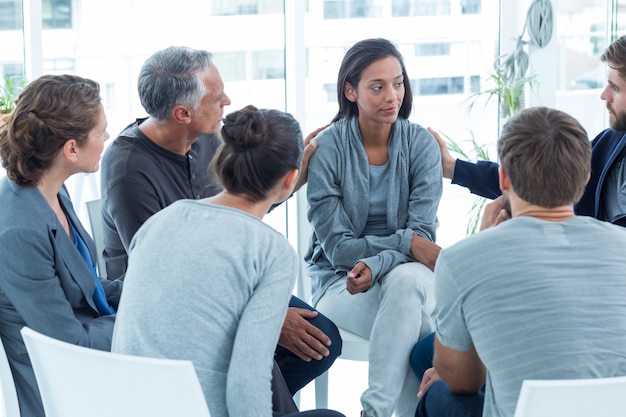 Homens preocupados confortando outro em grupo de reabilitação