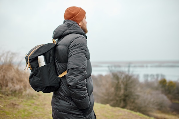 Homens que caminham com mochila e caminham ao longo das montanhas com vista para o rio