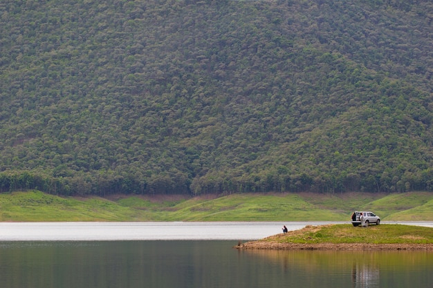 Homens sentados e pescando na ilha na barragem entre as montanhas.