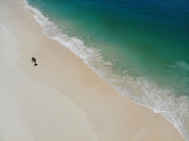 Homens sozinhos andar na praia no verão com ondas do mar clara e bela vista superior de cor por zangão